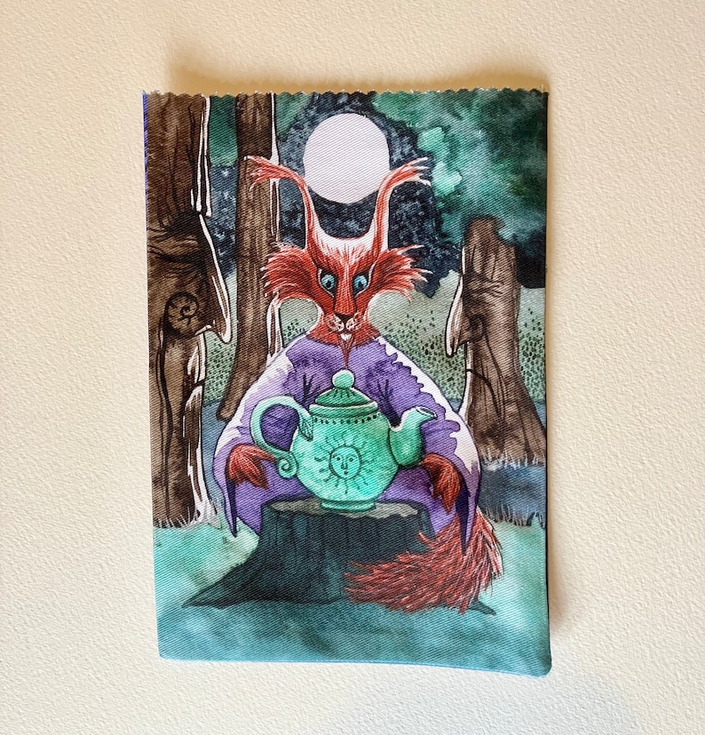 May include: A watercolor painting of a red fox wearing a purple robe and holding a green teapot with a sun design. The fox is sitting on a tree stump in a forest setting with a full moon in the background.
