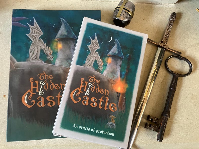 May include: Two copies of "The Hidden Castle" book with a castle and dragon illustration. A sword, key, and helmet are next to the books. The book cover has the text "The Hidden Castle" and "An oracle of protection".