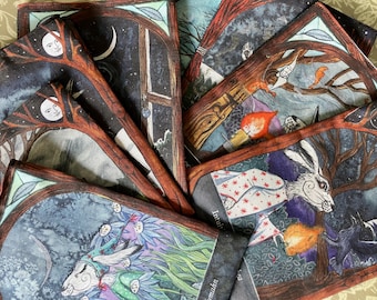 May include: A collection of rectangular fabric pouches featuring intricate illustrations of anthropomorphic rabbits, crescent moons, and dark forest scenes with brown tree-like borders. The artwork includes vibrant floral elements, glowing candles, and starry night skies.