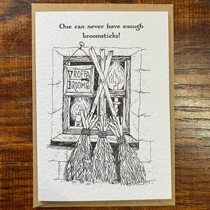 May include: A black and white illustration of a window with a sign that reads "VROFFA BROOMS" and three broomsticks sticking out of the window. The caption reads "One can never have enough broomsticks!"
