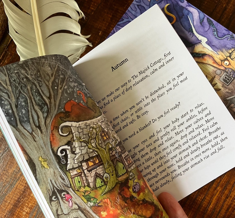 May include: An open book with the title "Autumn" and illustrations of a whimsical cottage and trees. A white feather rests on the book's edge. The pages contain text about relaxation and feeling calm.