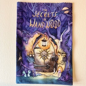 May include: A purple and blue illustrated book cover with the title "The Secrets of Wand Wood" in gold lettering. The cover features a whimsical illustration of a house with a door and a sun-like symbol above it.