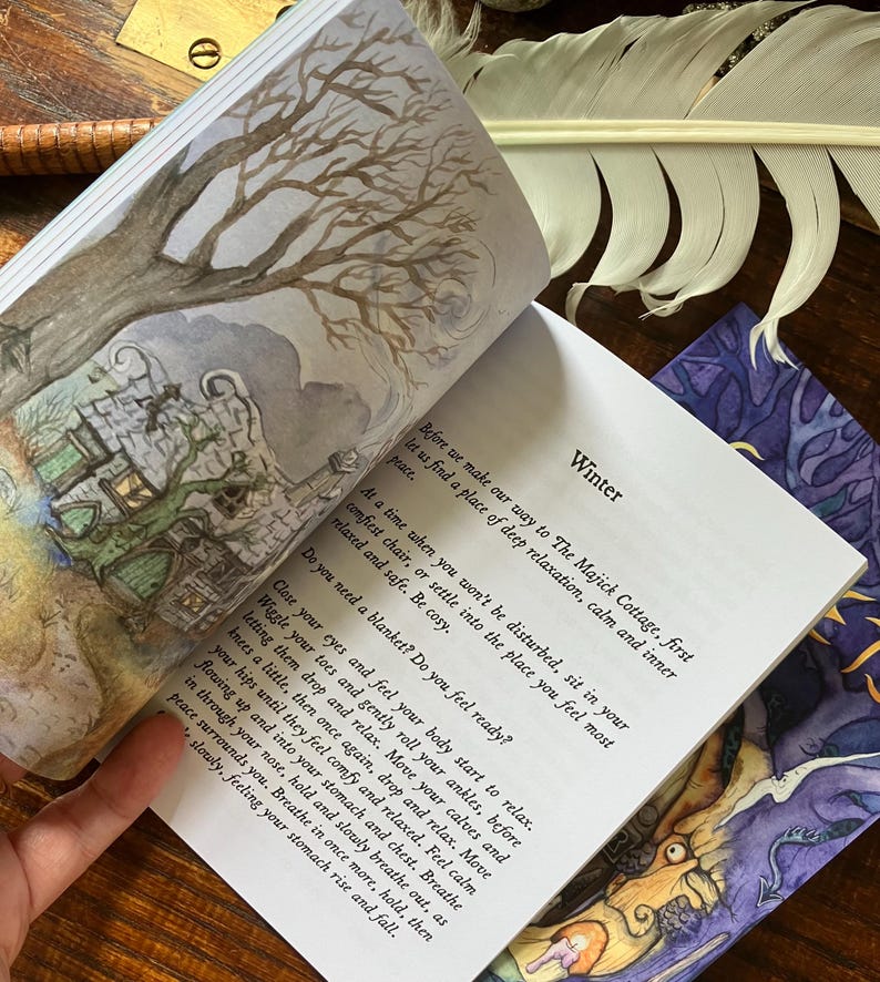 May include: Open book with watercolor illustrations and text. The left page features a drawing of a tree and a cottage. The right page has the word "Winter" and instructions for relaxation. A feather and other items are in the background.