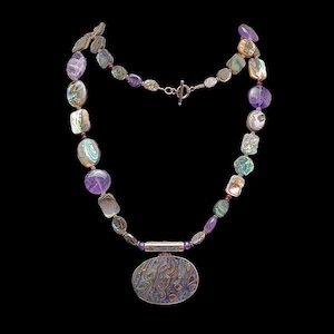 May include: A necklace featuring a large oval abalone shell pendant suspended from a silver-toned metal bar. The chain consists of alternating polished purple amethyst beads and iridescent abalone shell segments, secured with a silver-toned toggle clasp.