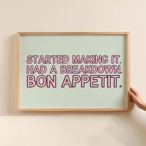 Peut inclure: Une impression encadrée avec un fond vert clair et un texte rose qui dit "Started making it. Had a breakdown. Bon Appetit."