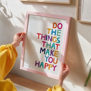 May include: A pink framed print with the text "Do the things that make you happy" in colorful letters.