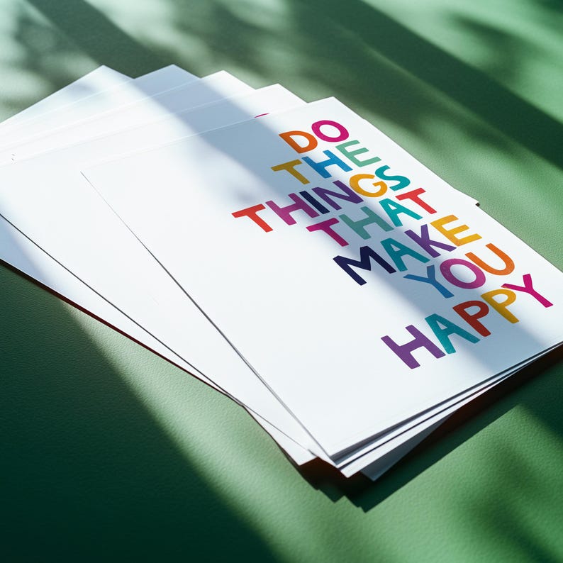 May include: A stack of white cards with the text "DO THE THINGS THAT MAKE YOU HAPPY" printed in colorful letters. The cards are arranged in a staggered pattern, with the top card slightly overlapping the one below it.