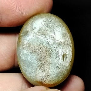 May include: A smooth, oval-shaped, light green and gold gemstone with a mottled pattern.