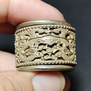 May include: Silver ring featuring an elaborate design of dragons and floral motifs. The ring is crafted from silver metal and has a polished finish.