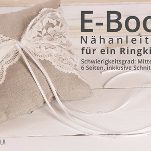 May include: A white lace ring pillow with a beige linen fabric base. The pillow is tied with a white satin ribbon. The text "E-Book Nähanleitung für ein Ringkissen Schwierigkeitsgrad: Mittel 6 Seiten, inklusive Schnittmuser" is printed on a white background.