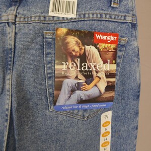 May include: Light blue Wrangler jeans, size 14 x 34, with a relaxed fit. The jeans have a tag with the Wrangler logo and the word "relaxed". The jeans are made of denim and have a classic five-pocket design.
