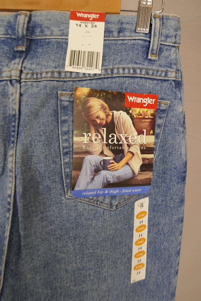 May include: Light blue Wrangler jeans, size 14 x 34, with a relaxed fit. The jeans have a tag with the Wrangler logo and the word "relaxed". The jeans are made of denim and have a classic five-pocket design.