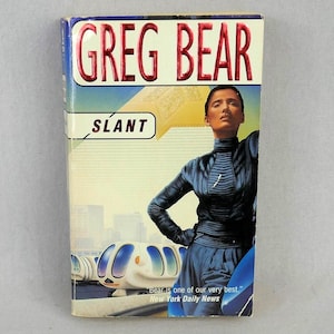 May include: A paperback book cover with a white background and a blue and black illustration of a woman wearing a black leather jacket and blue pants. The title of the book is "SLANT" by Greg Bear. The book cover also includes a quote from the New York Daily News.