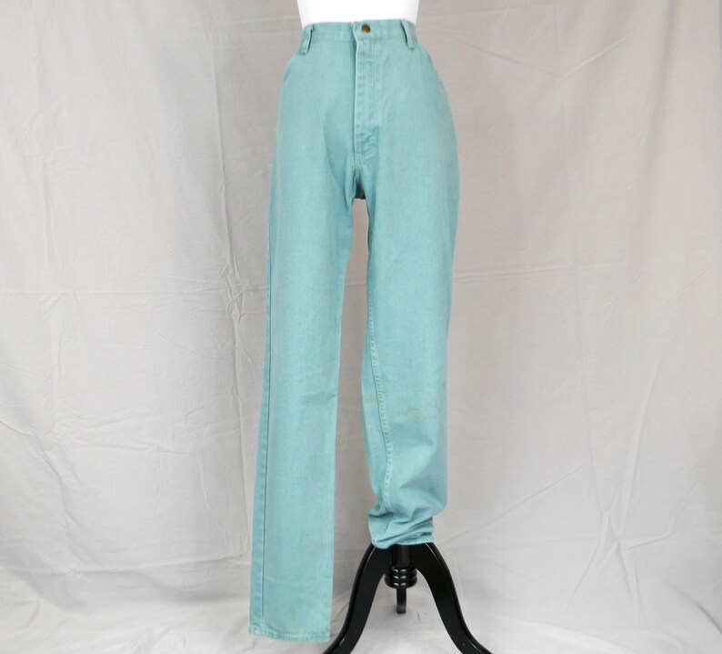 K&ouml;nnte beinhalten: Eine hoch taillierte, hellt&uuml;rkisfarbene Jeans. Die Jeans hat ein klassisches F&uuml;nf-Taschen-Design, einen Knopf- und Rei&szlig;verschluss und ein gerades Bein. Die Jeans wird auf einer schwarzen Schaufensterpuppe pr&auml;sentiert.