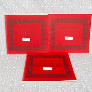 May include: Three red books with the title "Soldier's Millions" printed on the front cover. The books are on a white and gray patterned surface.