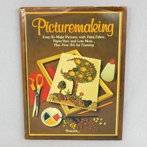 May include: A rectangular book titled Picturemaking: Easy-To-Make Pictures with Paint, Fabric, Paper, Yarn and Lots More... Plus How-To's for Framing. The cover features a craft project of a tree made from beans, scissors, glue, and paint.