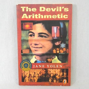 May include: A hardcover book titled "The Devil's Arithmetic" by Jane Yolen. The cover is predominantly red with a central image of a young person. Additional images and text are featured, including a National Jewish Book Award seal.