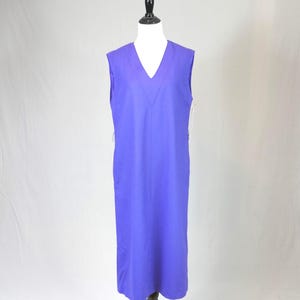 May include: A sleeveless, floor-length, purple dress with a V-neck. The dress is displayed on a mannequin against a plain white background. The dress has a simple, elegant design.