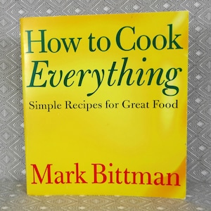 May include: A cookbook titled "How to Cook Everything" by Mark Bittman. The book has a bright yellow cover with green and red text. The cover also states "Simple Recipes for Great Food".