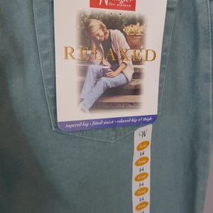 K&ouml;nnte beinhalten: Hellt&uuml;rkise Wrangler-Jeans mit einem Etikett mit der Aufschrift "Relaxed". Das Etikett zeigt ein Bild einer Person, die auf Stufen sitzt. Die Jeans hat ein schmales Bein, eine taillierte Taille und eine entspannte H&uuml;fte und Oberschenkel. Gr&ouml;&szlig;e 14.