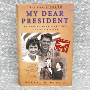 May include: A book titled "My Dear President" with the text "Letters Between Presidents and Their Wives." The cover features images of historical figures, including Ronald and Nancy Reagan, and Abraham and Mary Todd Lincoln. An "Air Mail" stamp is also visible.