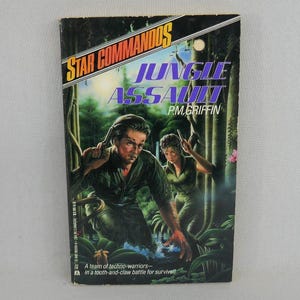 May include: A vintage paperback book titled "Jungle Assault" by P.M. Griffin. The cover art depicts two figures in green military attire in a jungle setting. The title is in purple and green, with the series name "Star Commandos" at the top.