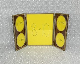 May include: A gold-toned metal triptych photo frame with a central rectangular panel and two hinged side panels. The center panel displays the text 8x10, while the side panels each feature two oval openings labeled 3x4.5 inches on yellow inserts.