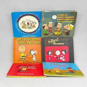May include: A collection of six vintage Peanuts books. Titles include "It Was A Short Summer, Charlie Brown", "He's Your Dog, Charlie Brown!", and "A Charlie Brown Christmas". The books feature colorful illustrations and text.
