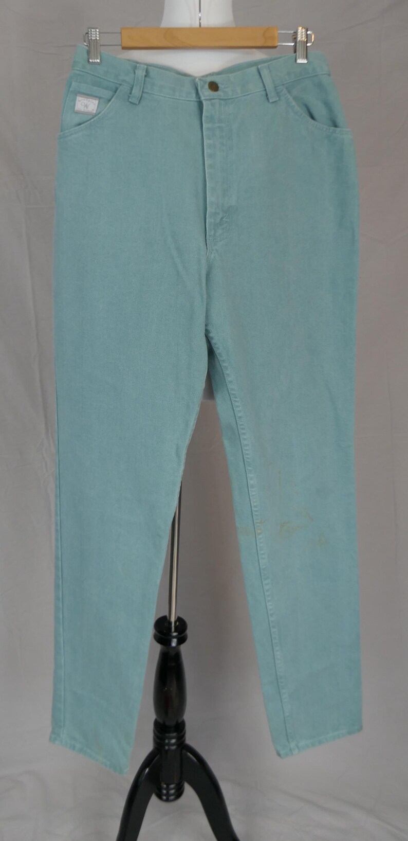 K&ouml;nnte beinhalten: Hellblaue Jeans mit klassischem F&uuml;nf-Taschen-Design. Die Jeans werden auf einer Schaufensterpuppe pr&auml;sentiert, die ihre gerade Beinpassform und den Knopfverschluss hervorhebt. Die Jeans haben ein verwaschenes Aussehen.