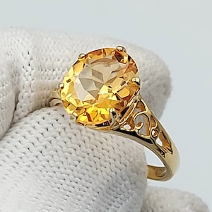 Peut inclure: Une bague en or avec une grande pierre de topaze jaune de forme ovale. La bague est ornée d'un motif délicat et filigrané.