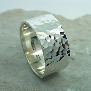 Peut inclure: Une large bague en argent avec une texture martelée. L'intérieur de la bande est estampillé "925" et "THAI 22".