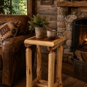 May include: A square side table constructed from light-colored, natural wood logs with a smooth, dark-toned wooden tabletop surface. The table features four sturdy log legs connected by a lower support frame, providing a stable base for the furniture.