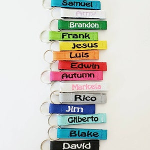 May include: A set of 14 colorful keychains with embroidered names, including Samuel, Brandon, Frank, Jesus, Luis, Edwin, Autumn, Maricela, Rico, Jim, Gilberto, Blake, and David.