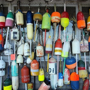 Puede incluir: Una colecci&oacute;n de boyas redondas de colores con varios n&uacute;meros y patrones colgando de una malla de alambre. Las boyas son de madera y est&aacute;n pintadas en colores brillantes, incluyendo rojo, amarillo, azul, verde y blanco.