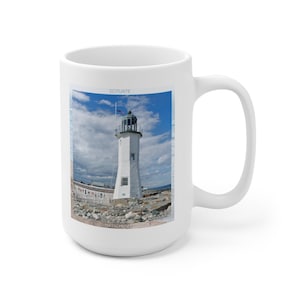 May include: White lighthouse with a green roof and a flag on a sunny day. The lighthouse is on a rocky shore with blue water in the background. The text "SCITUATE MASSACHUSETTS" is at the bottom of the image.