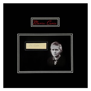 May include: A framed black and white portrait of Marie Curie, with her signature and the name "Marie Curie" in red script. The portrait shows a woman with short hair and a patterned blouse.