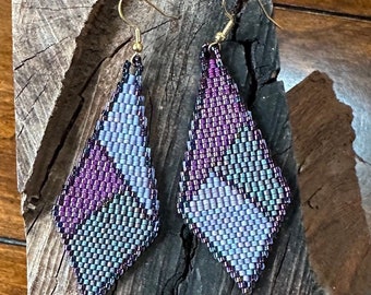 May include: A pair of dangle earrings with a geometric design. The earrings are made of purple and blue beads and have a silver finish.
