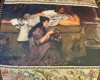 Puede incluir: Panel decorativo con una pintura clásica que representa a dos figuras. Una figura está reclinada en una cama, mientras que la otra está arrodillada, sosteniendo un arreglo floral. La obra de arte está enmarcada por un borde estampado con diseños florales y geométricos.