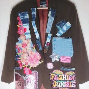 May include: A brown blazer featuring various patches including denim strips, a large pink floral embroidery, a sequined butterfly with the text GIRL, a silver star, a lipstick icon, and a heart patch with the text FASHION JUNKIE.