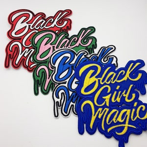 May include: Five embroidered patches with the words "Black Girl Magic" in different colors. The patches are in a stack, with the yellow and blue patch on top. The other patches are red, pink, and green.