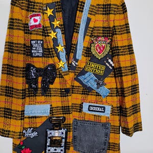 May include: A mustard yellow and black plaid blazer featuring various patches including gold stars, a black sequined bow, a red heart, a denim pocket, and text reading Born to Win, Don't Sit at Tables That Jesus Would Have Flipped, Limited Edition, Original, and a lil' bougie.