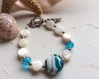 Beaded bracelet, seashell charm,  with the colors of the ocean waves.