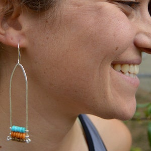 Puede incluir: Pendientes de aro de plata con un diseño de cuentas turquesa y naranja.