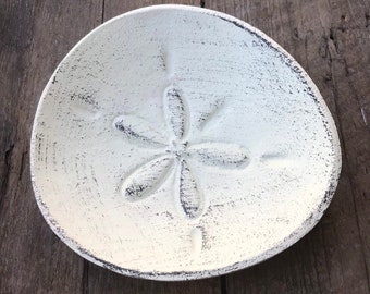 White sand dollar ring dish for your coastal home. This is a fun storage solution in the shape of a sand dollar. Shown in Cream Linen finish