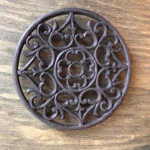 Round cast iron trivet and potholder with intricate and beautiful design made of cast iron