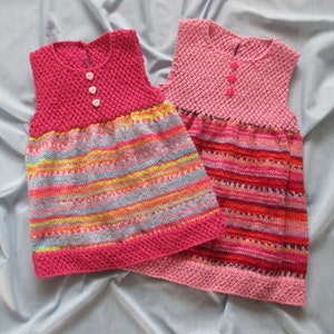 May include: Two sleeveless knitted dresses with pink and multi-colored stripes. The dresses have a pink bodice and a striped skirt.