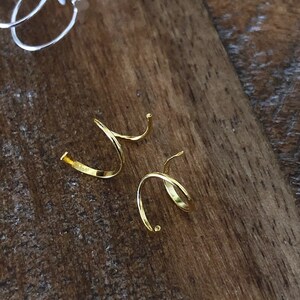 May include: Two gold-toned spiral ear cuffs. The cuffs are made of thin metal and have a simple, elegant design.