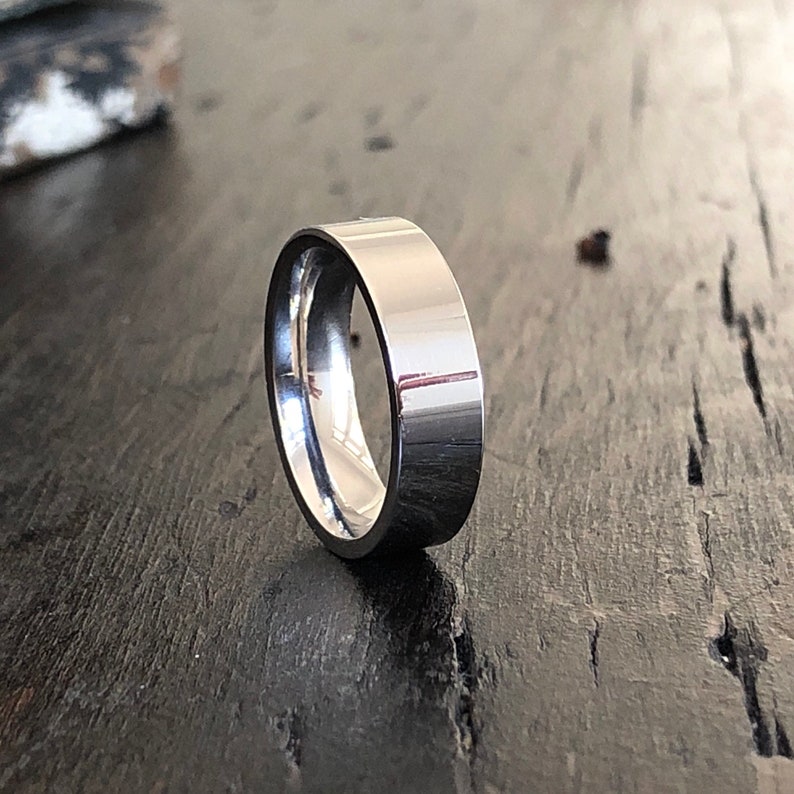 May include: A silver wedding band with a flat, polished finish.