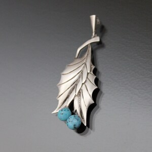 Peut inclure: Un pendentif en argent en forme de feuille avec deux pierres bleu turquoise.