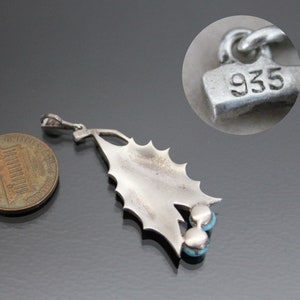 Peut inclure: Pendentif en argent sterling avec un motif de feuille de houx et trois pierres turquoise. Le pendentif est marqu&eacute; "935" au dos.